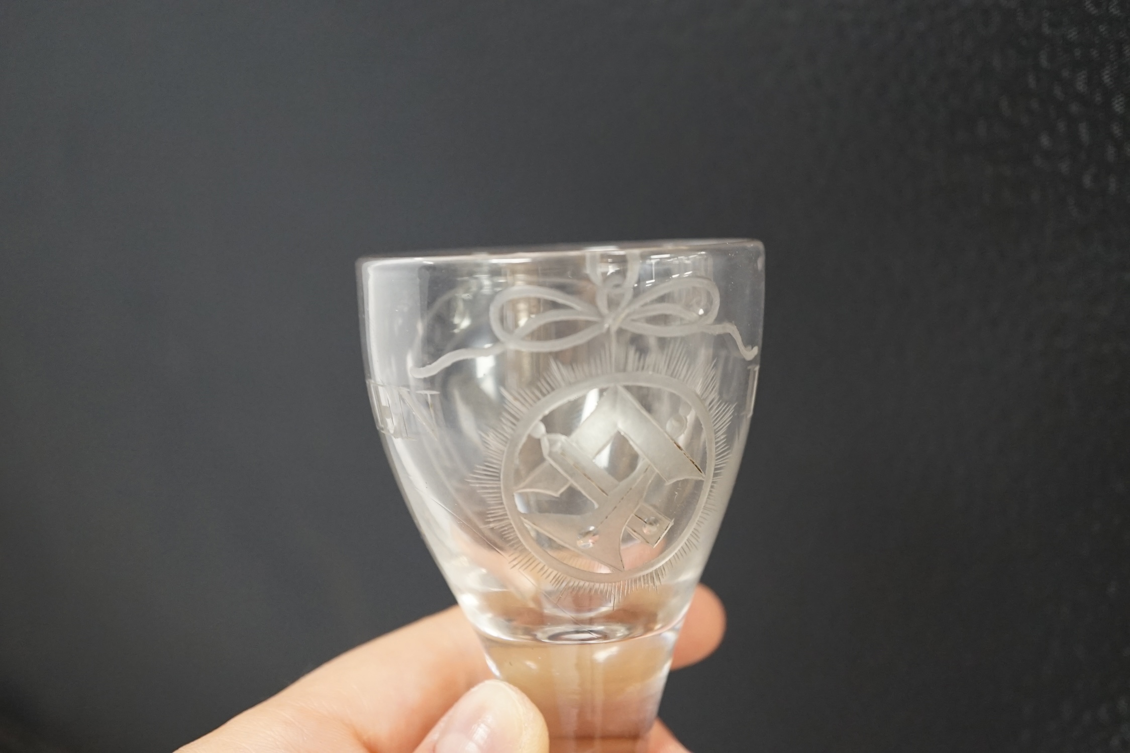 A George III Prince of Wales commemorative firing glass, early 19th century, finely wheel engraved with the Prince of Wales feathers, the motto ‘Spes. et. Dulce. Decus. Britannia’, ‘Ich Dien’ and Masonic motifs, 10.5cm h
